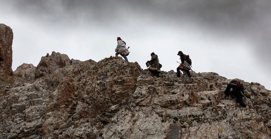 3 men walking on top of a rocky formation