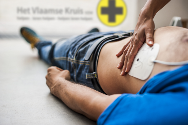 someone laying on floor, with a press pad on his side with a hand on the top of it