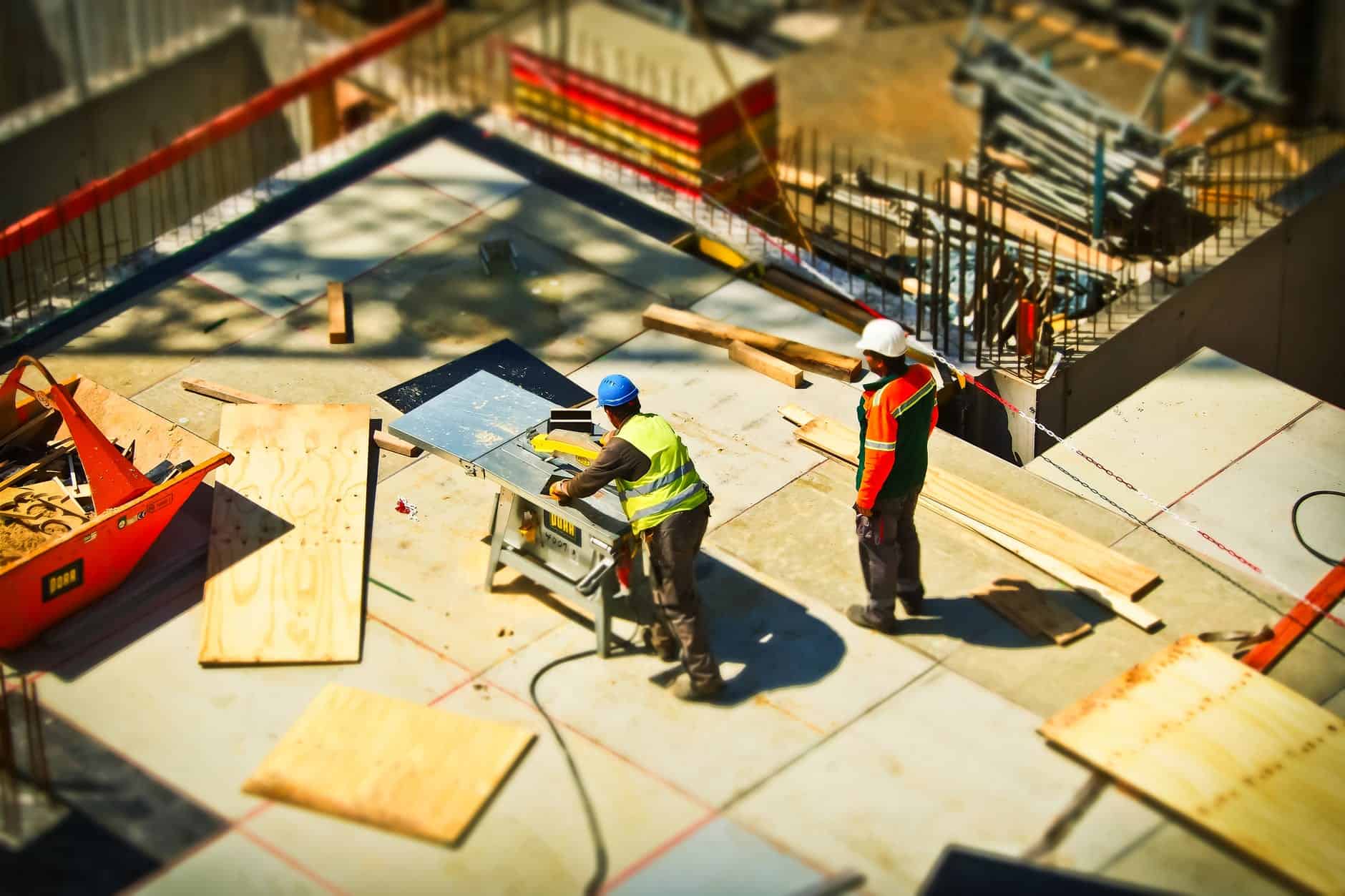 Two construction men complete with safety gears working at a construction site.