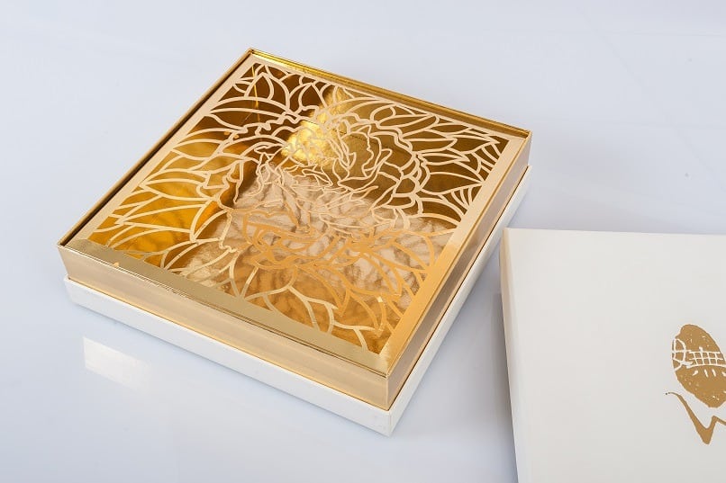A floral-designed golden box on top of its packaging.
