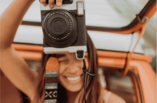 A close up of a lady taking a photo with a professional camera in her hands.