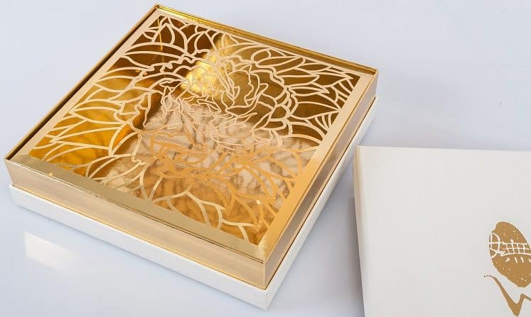 gold box sitting on top of its packaging with floral design