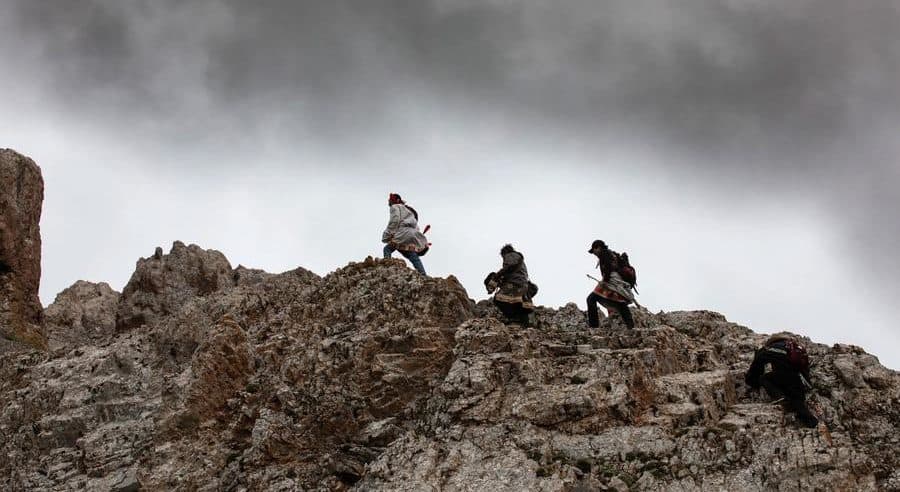 3 men walking on top of a rocky formation