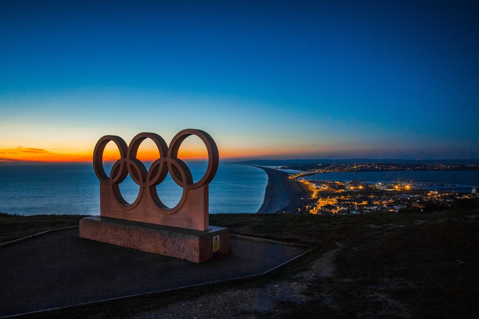 5 Olympic Rings with a lit up city in the background