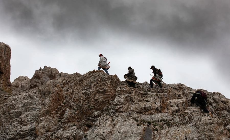 3 men walking on top of a rocky formation