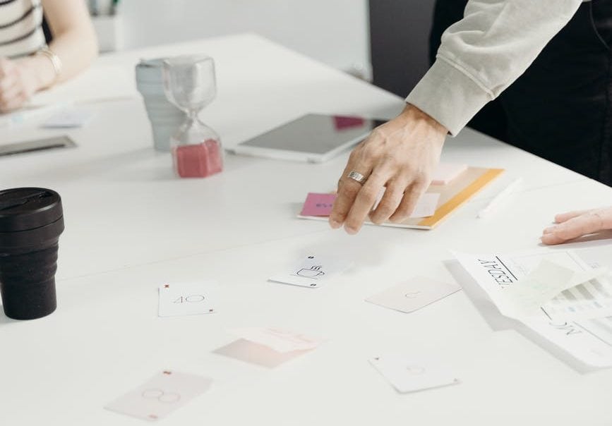 cards on a table looking to be planning, with mans hand moving them around on the table.