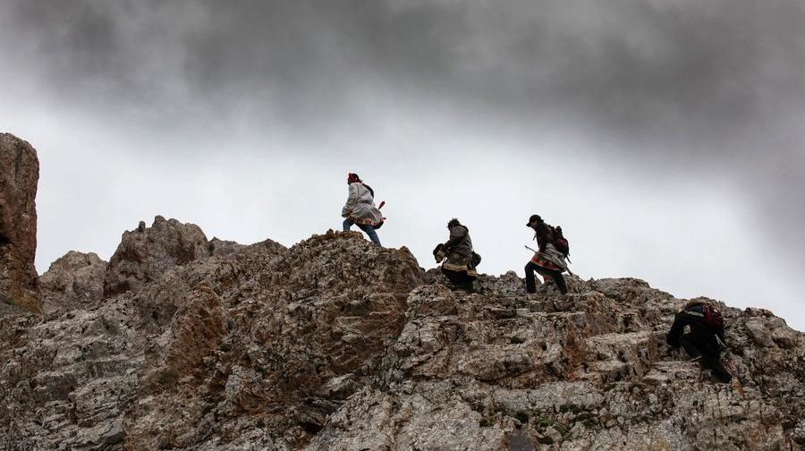 3 men walking on top of a rocky formation