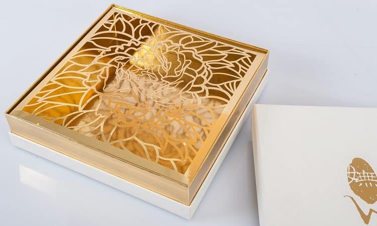 gold box sitting on top of its packaging with floral design