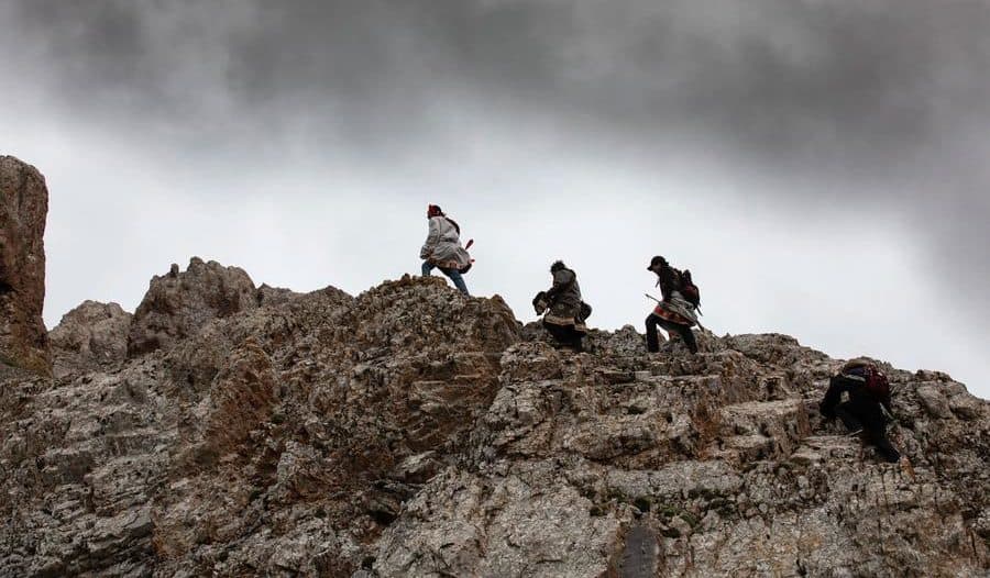 3 men walking on top of a rocky formation