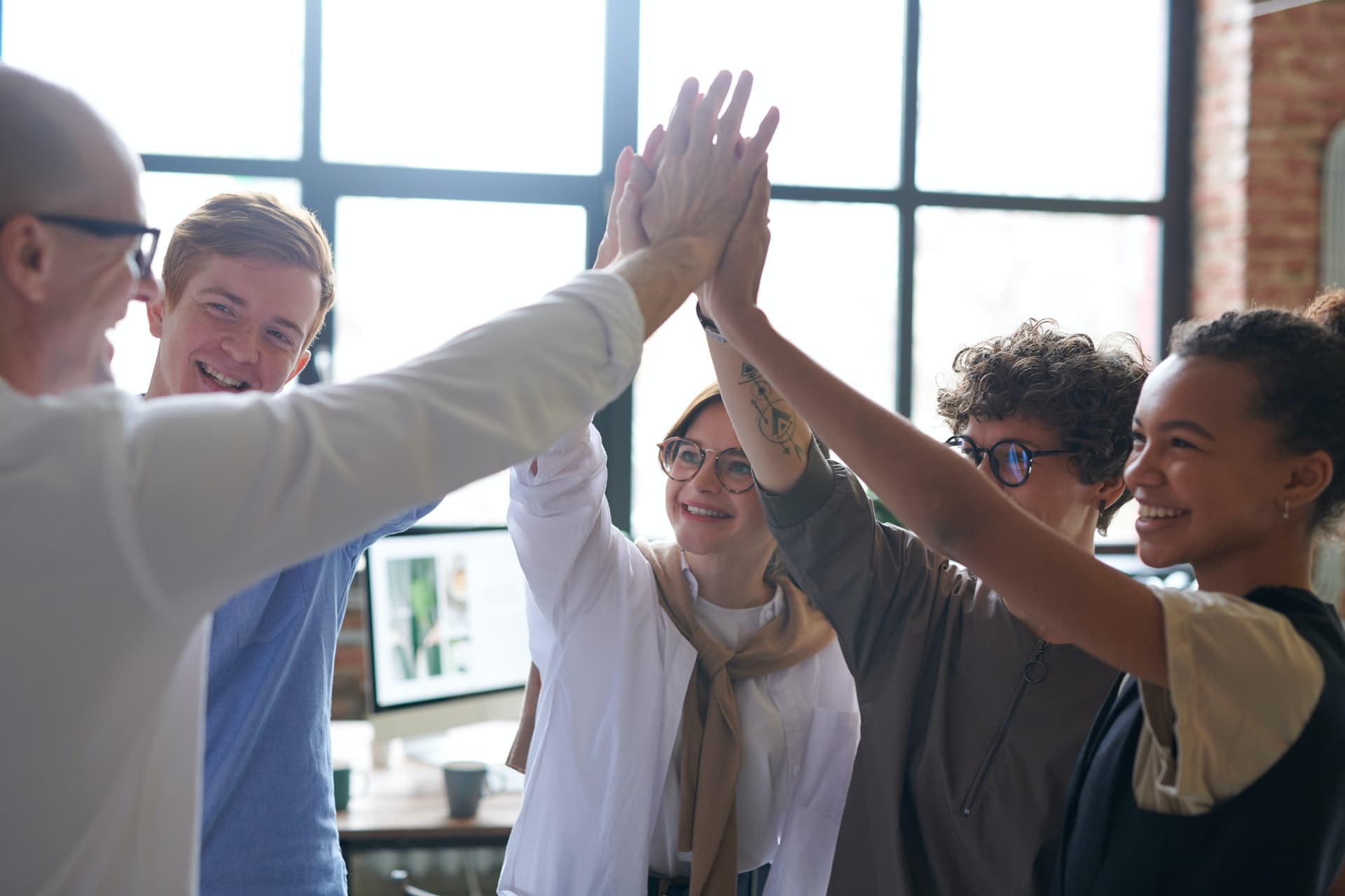 A group of people doing a group high five in an office.