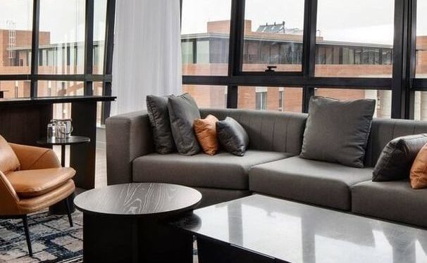 An open plan living room with a sofa and two coffee tables with a view looking onto a building.
