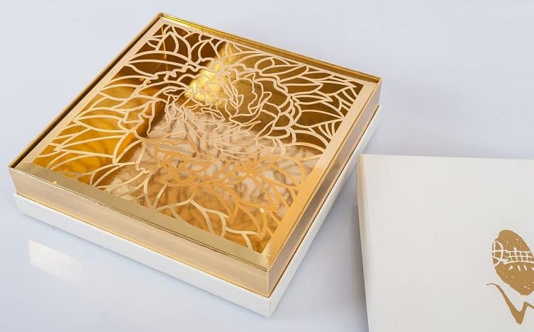 A white and gold coloured gift box with a floral design with the lid off.