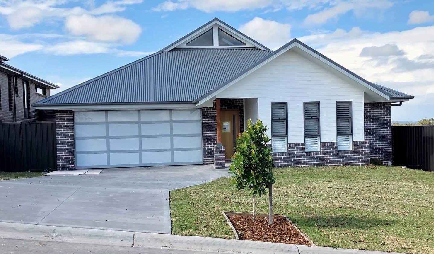 A newly built suburban house with a driveway and front lawn.