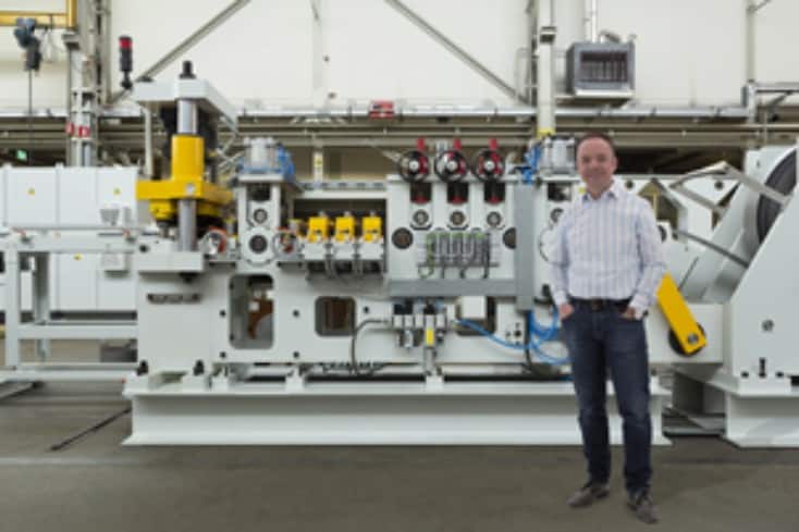 Kees Abbes, owner of Frontijne Holland standing in a factory in front of one of his machines.