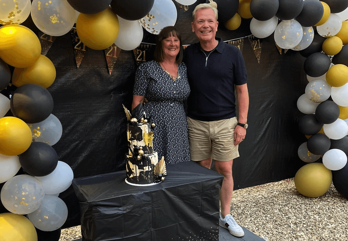 Colin and Julie Mills under a balloon arch, celebrating The CFO Centre's 21st birthday